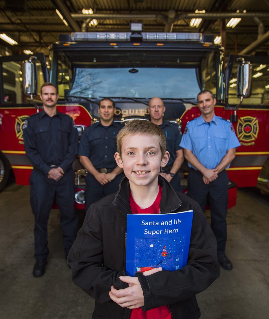 COQUITLAM,BC:NOVEMBER 29, 2016 -- Nathan McTaggart poses for a photo with the book and members of the Austin Heights Fire Station in Coquitlam, BC, November, 29, 2016. Nathan wrote about Santa getting stuck in the chimney and firefighters had to rescue him. (Richard Lam/PNG) (For Tracy Sherlock) 00046527A [PNG Merlin Archive]